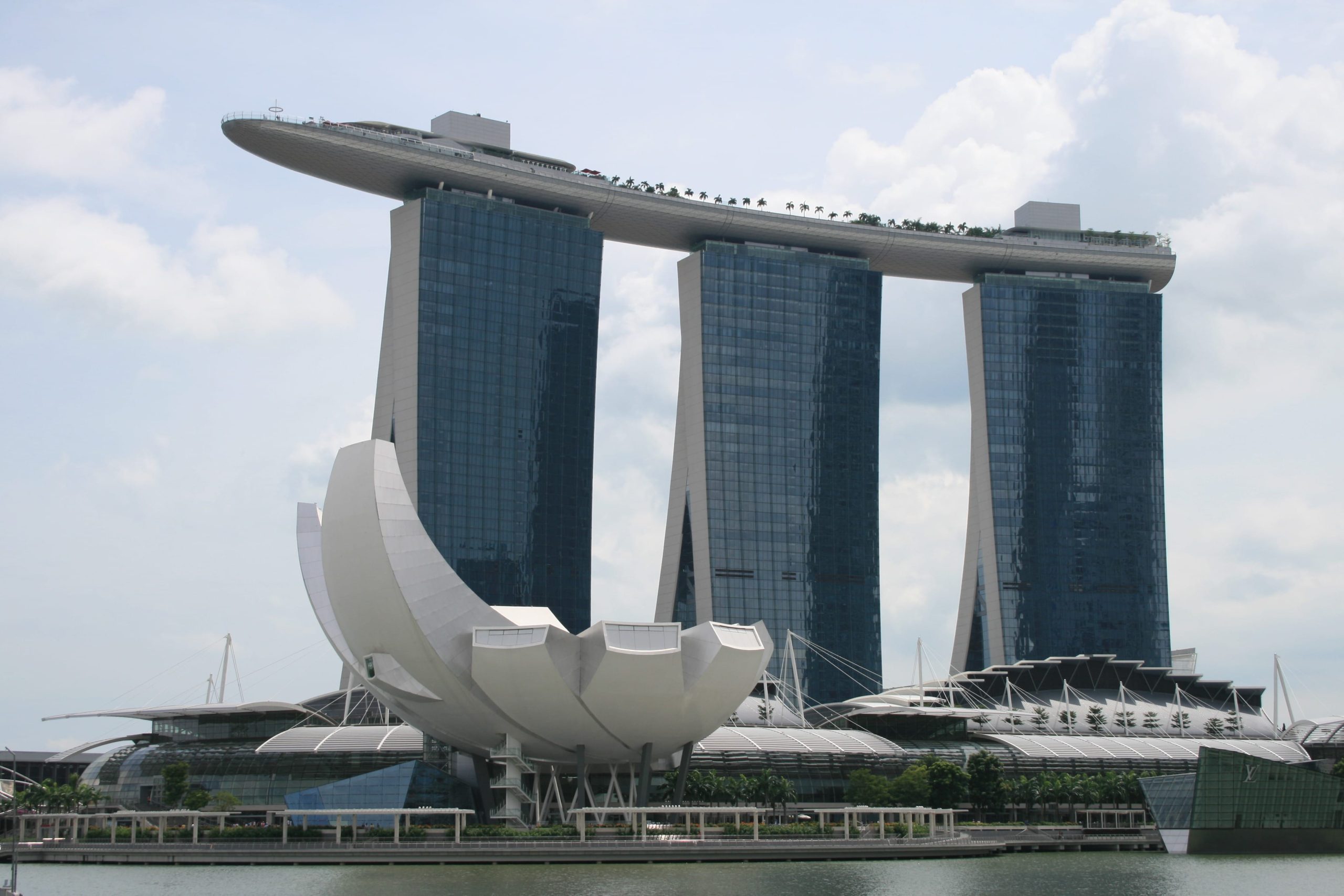 This image shows the futuristic architecture in Marina Bay Singapore. The tall building with the extended podium is the Marina Bay Sands SkyPark. This image is included to remind readers that not everything in Southeast Asia is chaotic and unorganised. Singapore is the complete opposite of chaos, with its highly regulated society  and forward looking vision. The links associated with the photograph provide the reader with information regarding how they might access the observation platform at the top of the SkyPark building.