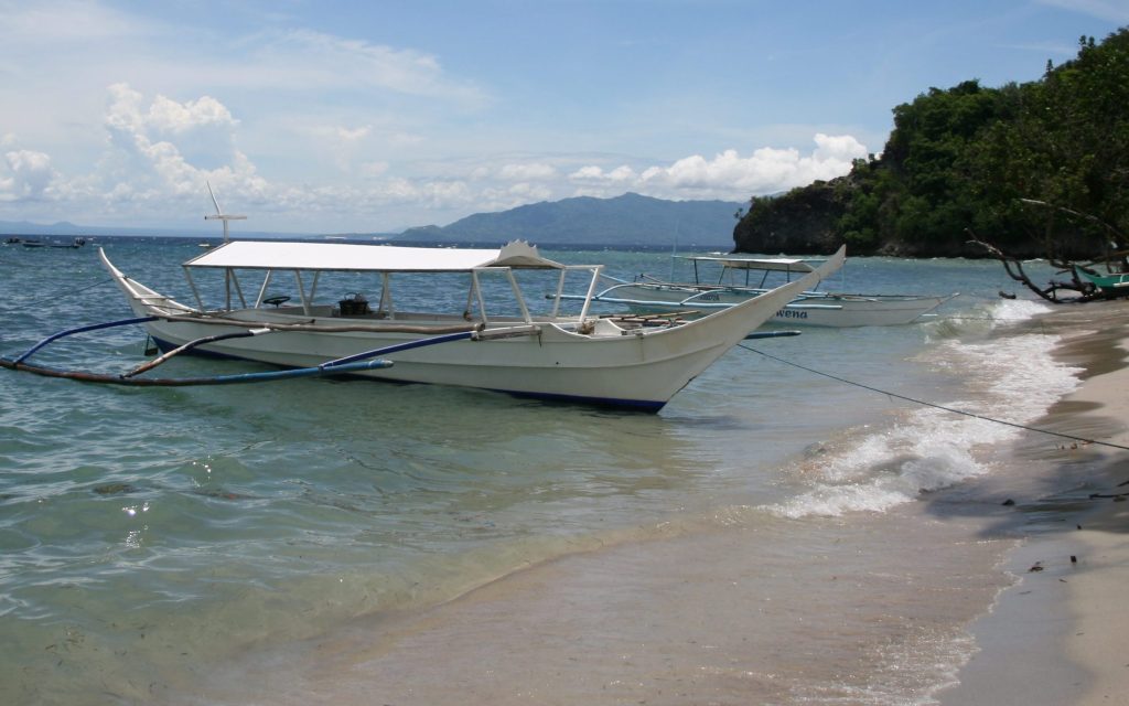 Small traditional filippino fishing boat at rest next to the beach at Alona Beach, Panglao, Bohol, Philippines