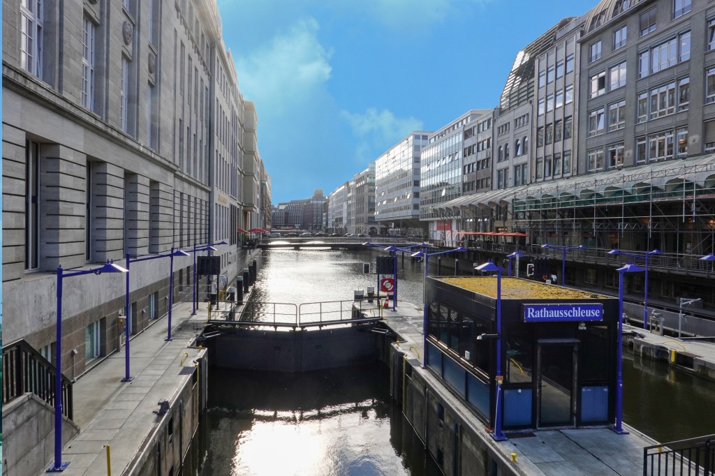 View of the Alsterfleet in Hamburg featuring the Rathaus-Schanze lock and modern buildings lining the water's edge.
