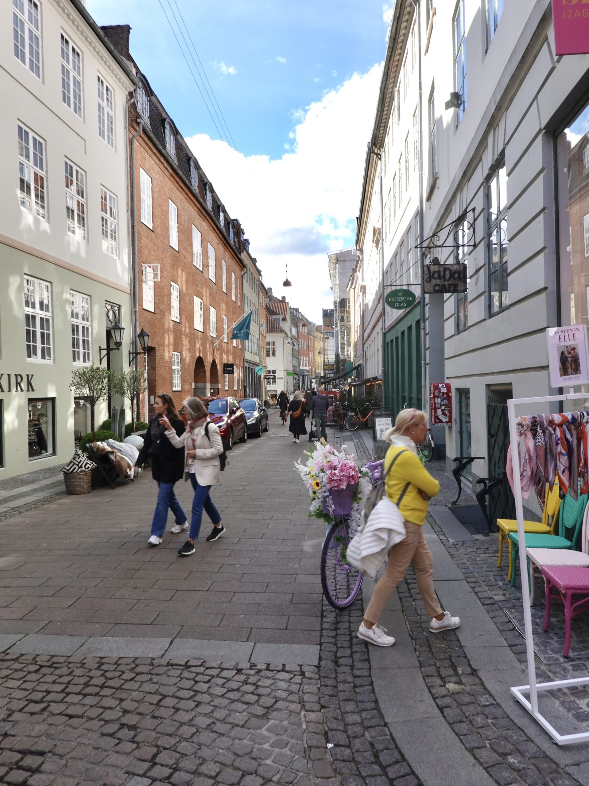 A view of a local cobble stoned neighbourhood street in central Copenhagen showing a collection of local retail shops and eateries. This local street lies between Stroget and Gammel Strand. It can be visited as part of the self guided walking route highlighted in this post.