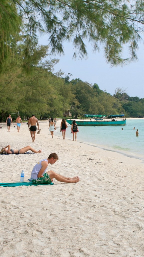 The  photo shows people relaxing on the beach at Kaoh Touch Beach, Koh Rong, Cambodia